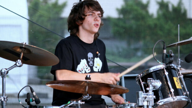 A young man is focused while playing the drums on stage during a live performance, HD Desktop Wallpaper