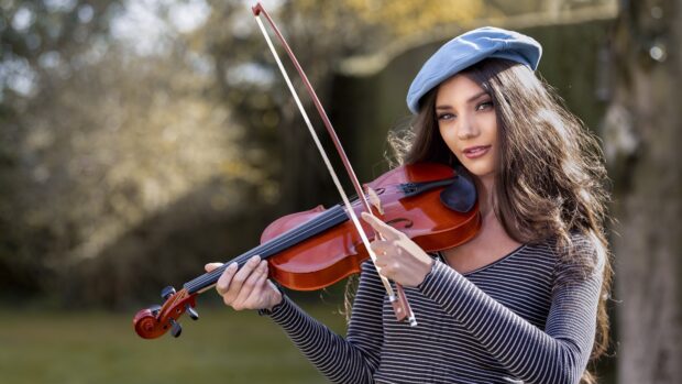A young woman playing violin in nature with a bow and wearing a blue beret, 4K Desktop Wallpaper
