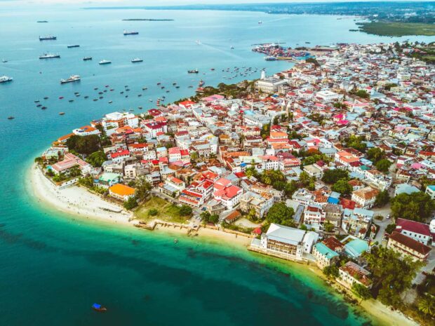 An aerial view showing Zanzibar city along the vibrant coastline and blue waters, HD Desktop Wallpaper