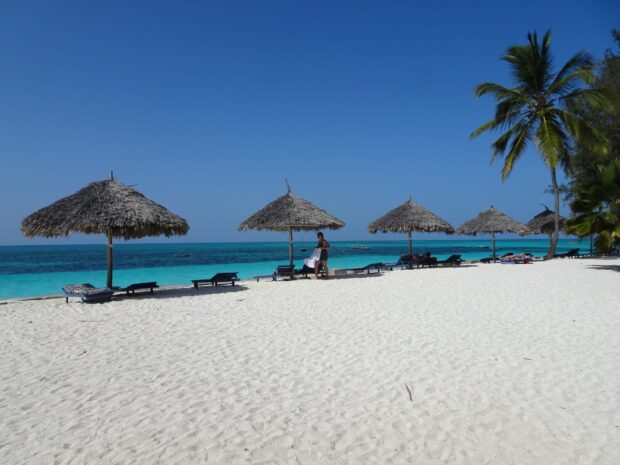 A peaceful beach with umbrellas and clear blue water in Zanzibar, HD Desktop Wallpaper