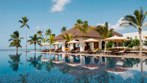 A tropical resort by the pool with palm trees reflecting in the water in Zanzibar wallpapers, HD Desktop Wallpaper