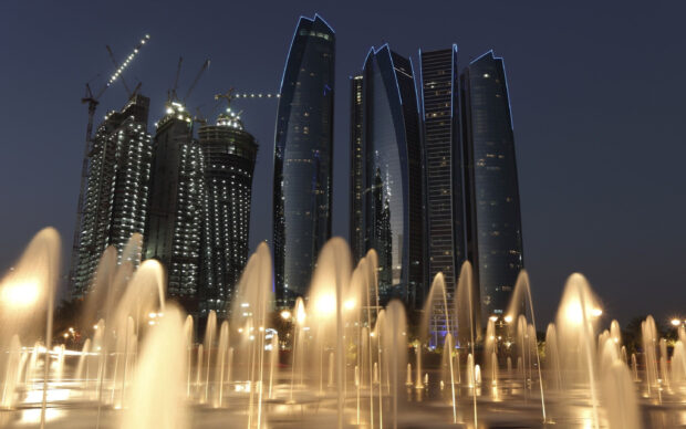 Night view of Abu Dhabi cityscape with illuminated skyscrapers and fountains