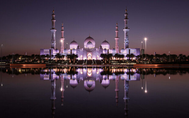 Sheikh Zayed Mosque in Abu Dhabi reflecting on calm water at dusk