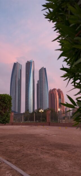 Modern skyscrapers in Abu Dhabi under a pink sky at sunset
