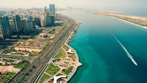 Aerial view of Abu Dhabi cityscape with waterfront and boats on clear turquoise water