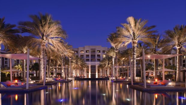 Luxury resort with palm trees and pool in Abu Dhabi at night