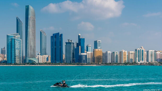 Modern Abu Dhabi skyline with skyscrapers and people riding a jet ski on the water
