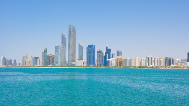 The Abu Dhabi city skyline with modern skyscrapers along the turquoise water coast