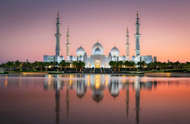 Sheikh Zayed Mosque architecture in Abu Dhabi during sunset with clear sky and reflecting water