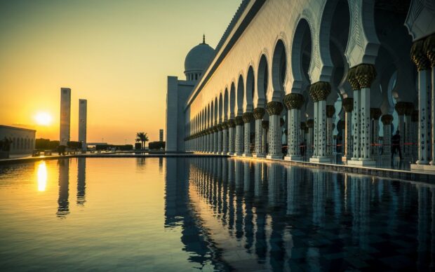 Sunset over Abu Dhabi mosque with reflective water and detailed arches