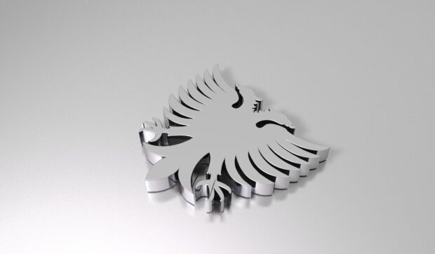 A metallic emblem of Albania with a double headed eagle design on a silver surface