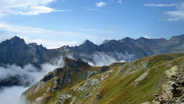 Rocky mountain landscape in Albania with clouds rolling through the peaks and a clear blue sky