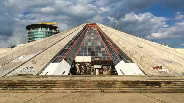 The pyramid shaped building in Albania with street art and cloudy sky in the background
