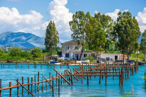 A serene Albanian landscape with a wooden pier extending over turquoise water and green trees