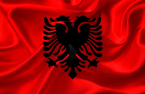 A close up of the Albania flag with a black double headed eagle on red fabric