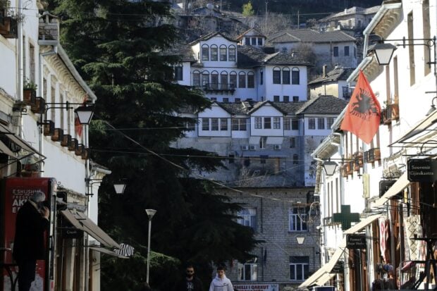 Traditional Albanian buildings and stone houses in a historic town with the Albanian flag displayed