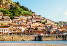 Traditional Albanian houses built on a hillside beside a river in a scenic town