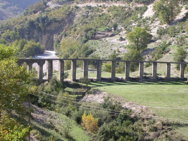 An ancient stone aqueduct crossing a green valley in Albania landscape