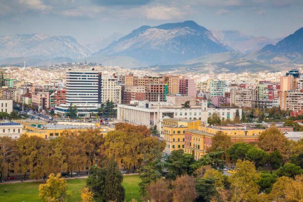 Autumn cityscape of Tirana with buildings and mountains in the background