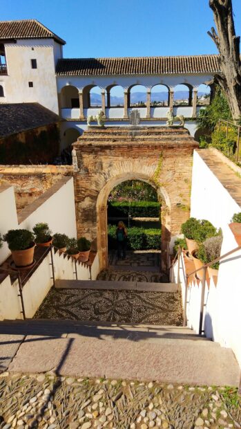 Ancient Alhambra archway with stone steps and garden view in sunlight