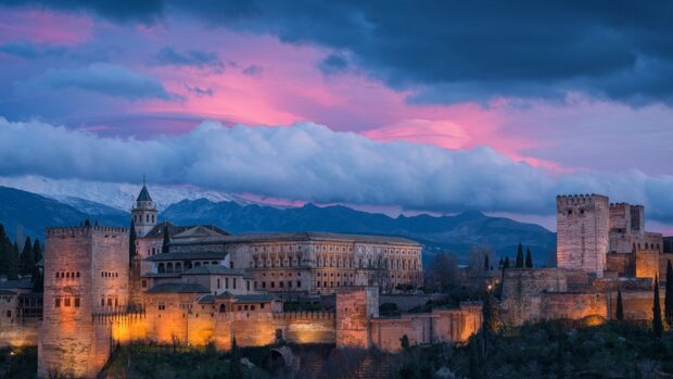The Alhambra with mountains and colorful sky at sunset in a beautiful landscape