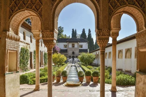 Ornate arches and lush garden with fountains at Alhambra palace