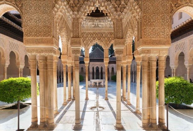 The Alhambra architecture features intricate stone carvings and elegant columns in a historic courtyard