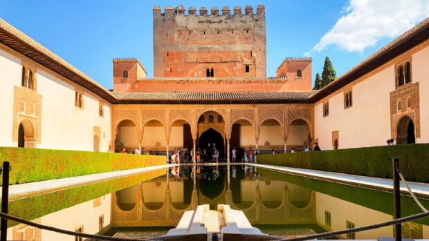The Alhambra architecture with reflective pool and arches in a sunny day