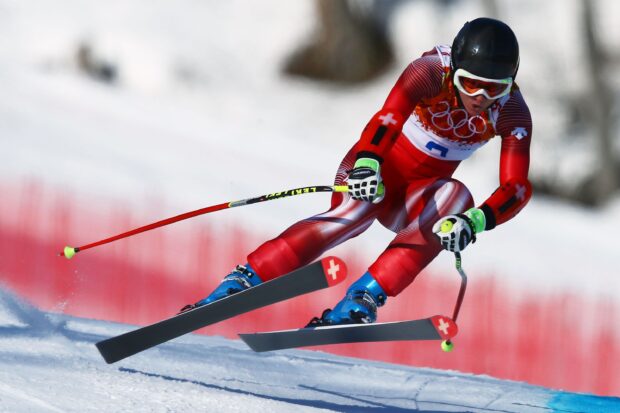 A professional alpine skiing athlete racing down a snowy slope in a red suit