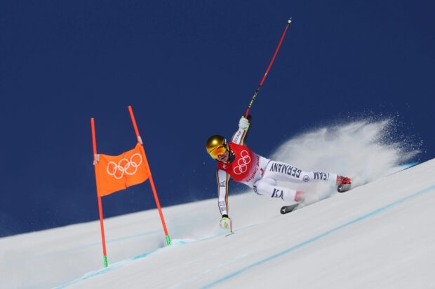 Professional alpine skier racing down a snowy slope during a competition