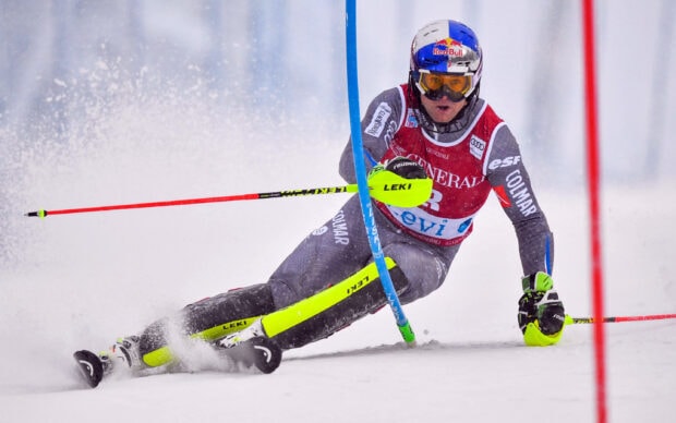 Professional alpine skiing athlete racing through slalom gates on snowy slope
