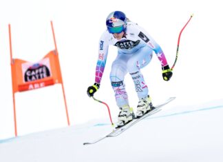 A professional alpine skier racing down a snowy slope in a fast position