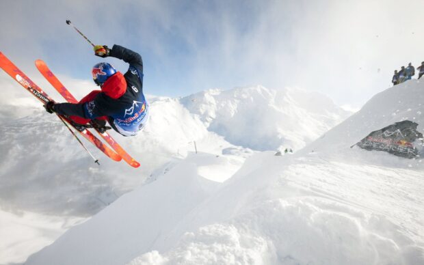A skier performing an airborne trick during an alpine skiing event in snowy mountains
