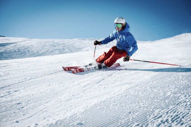 A skier wearing a helmet and goggles skiing down a snowy slope practicing alpine skiing skills