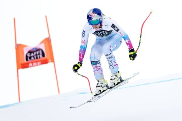 A professional alpine skier racing down a snowy slope in a fast position