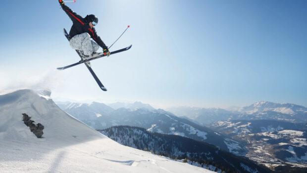 Skier performing a jump in alpine skiing over a snowy mountain slope