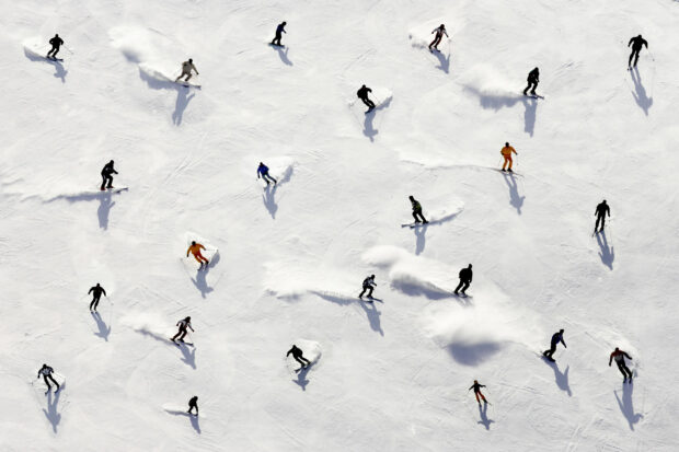 A group of alpine skiing athletes descending a snowy mountain slope in various colorful outfits