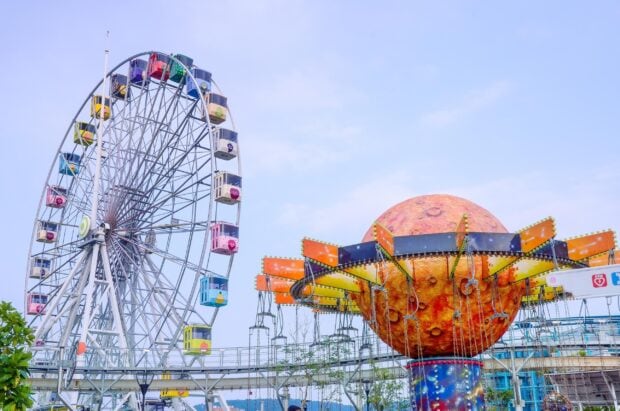 A colorful amusement park ride with a Ferris wheel and swinging chairs under a clear sky