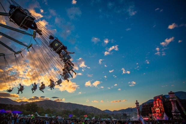 People enjoying swing ride at amusement park during sunset with scenic mountains in the background