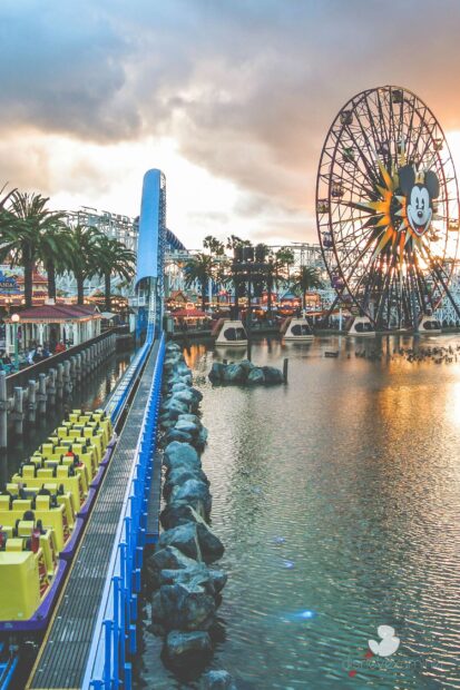 A roller coaster track near a large ferris wheel at an amusement park during sunset
