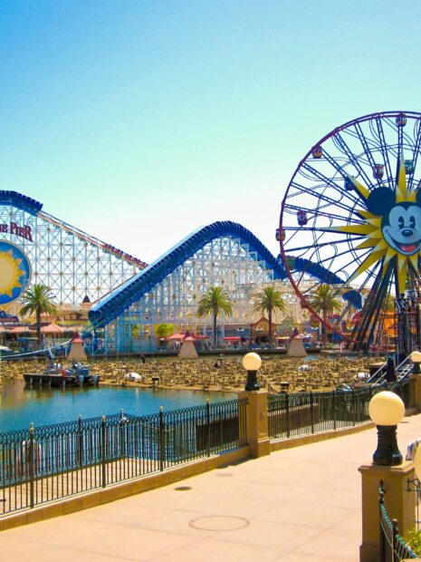 A roller coaster and Ferris wheel at an amusement park under clear blue sky