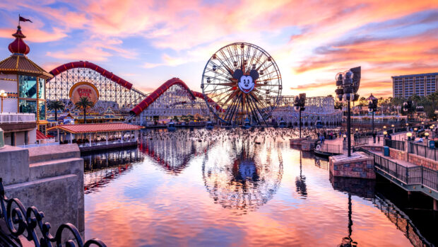A vibrant amusement park with a large ferris wheel and roller coaster at sunset