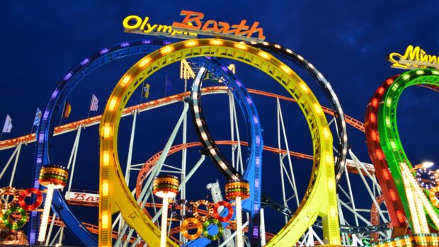 Colorful amusement park rides with loops at night under a dark blue sky