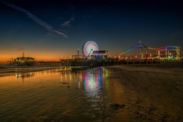 A colorful amusement park at sunset reflecting on the wet sandy beach