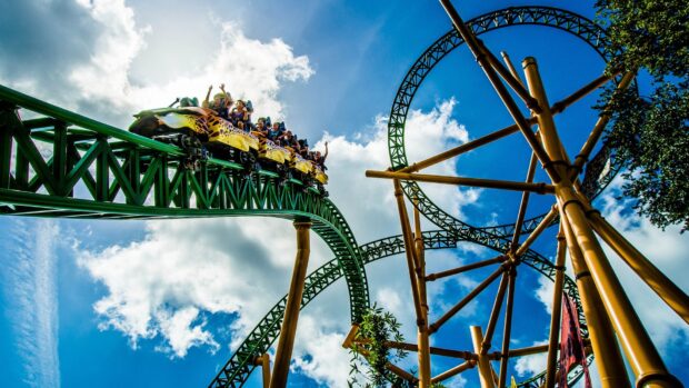 People enjoying a roller coaster ride at an amusement park with blue sky background