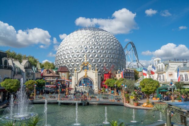 A large dome and amusement park attractions with a fountain in front of the amusement park