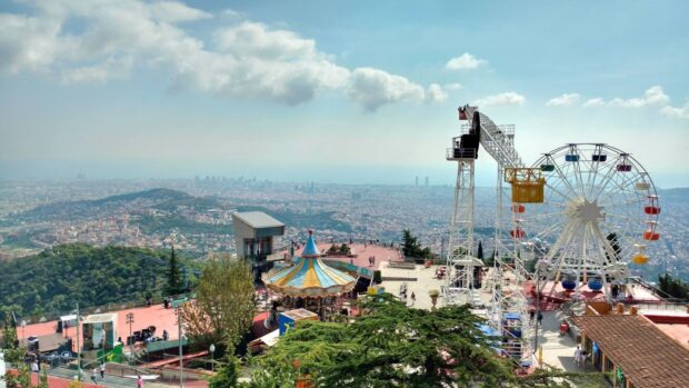 A scenic amusement park with a ferris wheel and carousel overlooking the cityscape