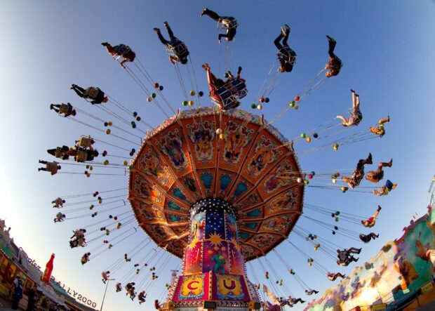 Colorful amusement park ride with people swinging high on a sunny day in the amusement park