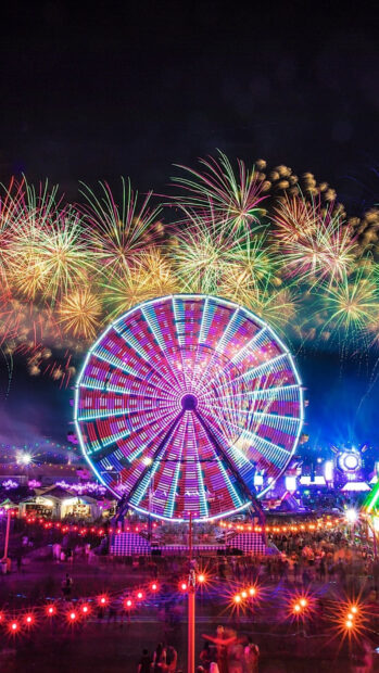 Colorful Ferris wheel with vibrant fireworks over the amusement park at night