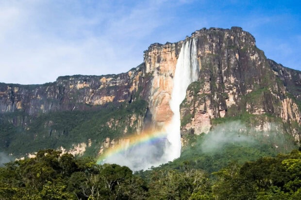 Angel Falls waterfall with rainbow over the lush forest and rocky cliff